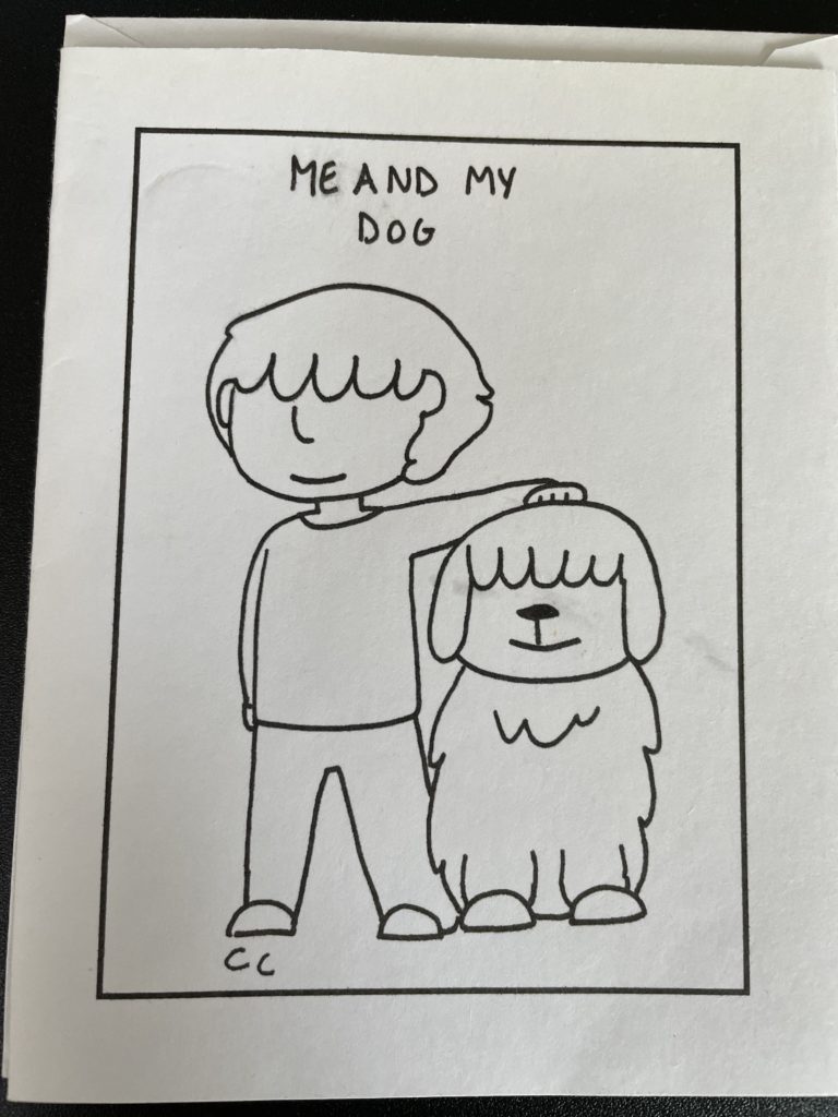 A vertical line drawing, black marker on white paper. Inside a drawn rectangle frame, at top, in all capital letters, handwritten, it says, “ME AND MY DOG.” The main image is of a person standing next to a dog, with their hand on the dog’s head. Both human and dog have shaggy bangs that cover their eyes. 