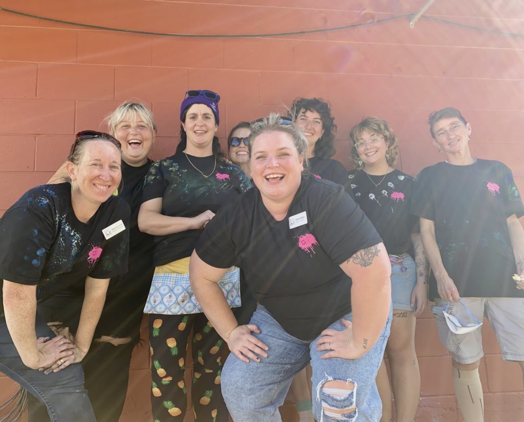 photograph of Inclusive Arts Vermont staff and board members outside in front of a brick wall in black t-shirts.