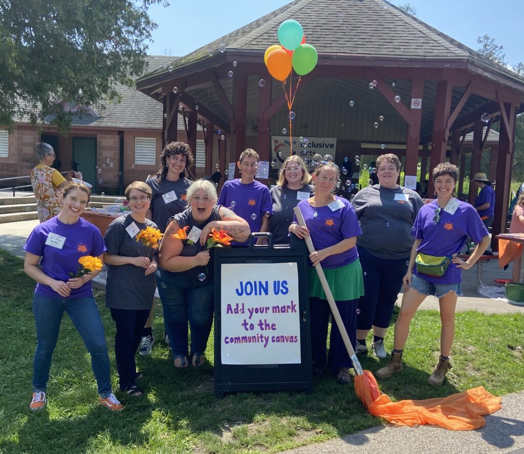 A photograph of Inclusive Arts Vermont staff and board members at the POP fundraiser outside. Everyone is smiling and there are bubbles in the air.