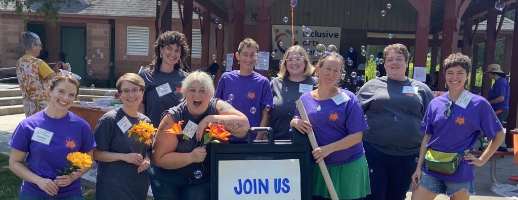 A group photo of the IAV board and staff at a recent outdoor fundraiser. Everyone is smiling and there are bubbles in the air. 