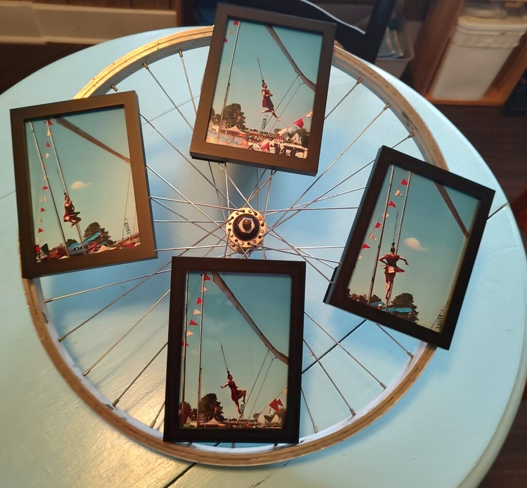 a bicycle wheel with 4 photos attached. Photos show an aerial performer swinging from her hair.
