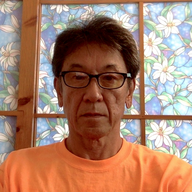 Headshot of Asian male with black short length hair, wearing black frame glasses and orange t-shirt in front of a backdrop of a stained-glass panel with a blue field and white flowery vines.